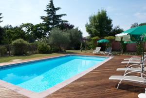 a swimming pool with chairs and umbrellas on a wooden deck at Hôtel Le Barry, Toulouse Nord in Gratentour