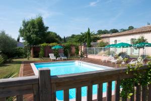 a swimming pool on a wooden deck next to a house at Hôtel Le Barry, Toulouse Nord in Gratentour
