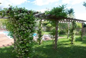 a pergola covered in flowers in a yard at Hôtel Le Barry, Toulouse Nord in Gratentour