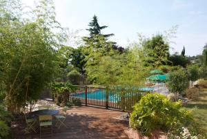 a garden with a fence and a swimming pool at Hôtel Le Barry, Toulouse Nord in Gratentour
