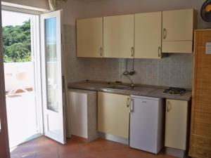 a kitchen with white cabinets and a sink and a door at L'Isolana Case Vacanza Luna 1 in Ponza
