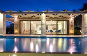 a house with a swimming pool at night at Avra Luxury Villa & Spa in Keri