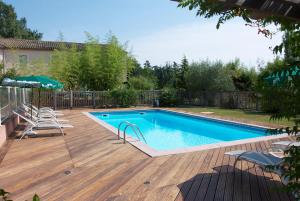 a swimming pool on a wooden deck with at Hôtel Le Barry, Toulouse Nord in Gratentour