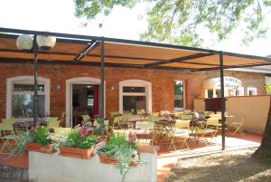 a patio with tables and chairs and a brick building at Hôtel Le Barry, Toulouse Nord in Gratentour