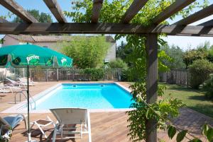 a pool with a table and chairs and an umbrella at Hôtel Le Barry, Toulouse Nord in Gratentour
