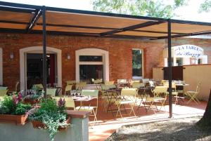 a patio with tables and chairs in a brick building at Hôtel Le Barry, Toulouse Nord in Gratentour