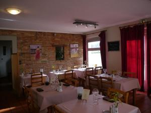 a dining room with white tables and chairs and a brick wall at Hôtel Le Barry, Toulouse Nord in Gratentour