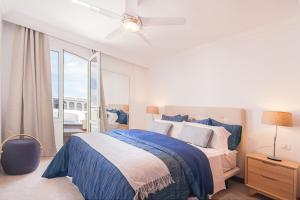a white bedroom with a blue bed and a window at Rooms & Suites Terrace 4D in Arrecife