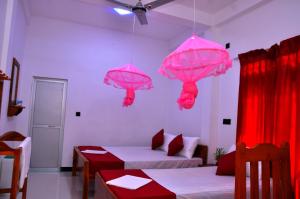 um quarto com guarda-sóis rosa pendurados no tecto em Hilton Cottage em Trincomalee