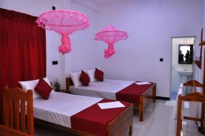 een kamer met 2 bedden en roze parasols op de muur bij Hilton Cottage in Trincomalee