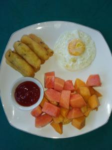 a plate of food with eggs and fruit on a table at Sunset Guest House & Bar in Bunaken