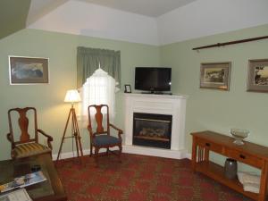 sala de estar con chimenea, 2 sillas y TV en Kearsarge Inn en North Conway