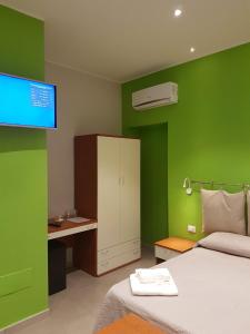 una camera da letto con pareti verdi, un letto e una scrivania di A due passi dal mare a Marina di Schiavonea