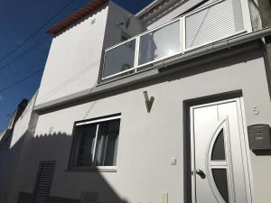 a white house with a window and a door at Loft-Entre a praia e o campo in Nazaré