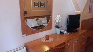 a bedroom with a mirror and a desk with a television at Hotel Isabell Győr in Győr