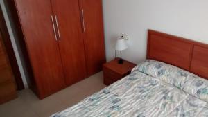 - une chambre avec un lit, des armoires en bois et une lampe dans l'établissement Apartamento en Águilas, à Águilas