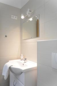 a white bathroom with a sink and a mirror at Forrás Ház Tapolca in Tapolca