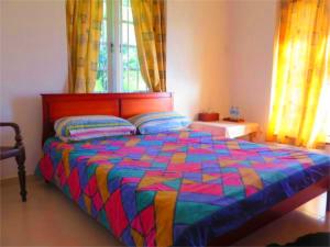 a bed with a colorful comforter in a bedroom at Blackpool 55 in Nuwara Eliya