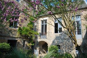 una casa de piedra con flores púrpuras delante de ella en Hôtel Tanquerey de La Rochaisière, en Coutances