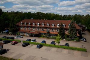 un gran edificio con coches estacionados en un estacionamiento en Haags Hotel Niedersachsenhof en Verden