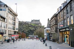 una calle en una ciudad con un castillo en el fondo en Beautiful City Centre Apartment - Holyrood Park en Edimburgo