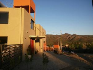 a white building with a red door on a street at Complejo Riro Namaste in San Antonio de Arredondo