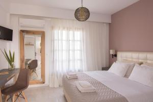 a bedroom with a large white bed and a desk at The Wave in Sidari
