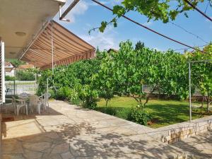 eine Terrasse mit einem Tisch, Stühlen und Bäumen in der Unterkunft Apartmani Mlinar in Gornji Karin