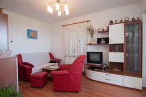 salon z 2 czerwonymi krzesłami i telewizorem w obiekcie Dragica w mieście Lovran