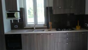 a kitchen with wooden cabinets and a sink and a microwave at Villa Cohiba - 700m dal mare in Pulsano