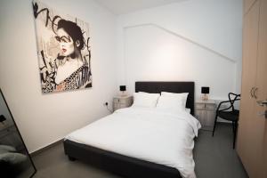 a bedroom with a white bed and a painting on the wall at MCPlaces Holiday Apartments in Paphos