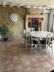 uma sala de jantar com mesa e cadeiras e um relógio em Maison de charme em Concourson-sur-Layon