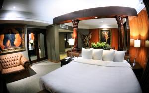 a bedroom with a large bed and a chair at Hotel Real de Don Juan in Tepic