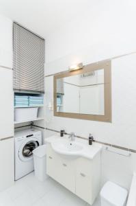 ein weißes Badezimmer mit einem Waschbecken und einer Waschmaschine in der Unterkunft Apartment ''Pomalo'' in Split + 17 Fotos