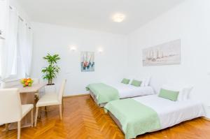 2 Betten in einem Zimmer mit einem Tisch und einem Schreibtisch in der Unterkunft Apartment ''Pomalo'' in Split