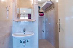 a bathroom with a sink and a shower with a mirror at Apartman Studio in Pula