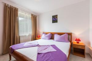 a bedroom with a large bed with purple pillows at Apartman Studio in Pula