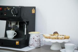 a coffee maker with a plate of donuts and cups at Art in B&B in Salerno