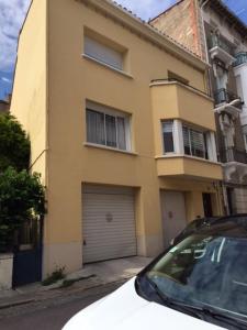 une voiture garée devant une maison jaune dans l'établissement Casa Oliva -situé au 2ème étage sans ascenseur, à Perpignan