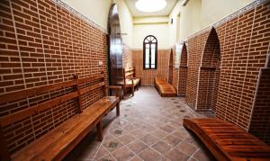 a row of wooden benches in a brick room at Hotel Club Hanane in Ouarzazate