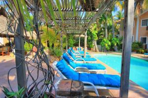 a row of blue lounge chairs next to a swimming pool at Hotel Santa Fe in Puerto Escondido