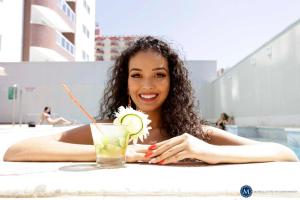 a woman laying in a pool with a drink at Everest Flat Service in Caldas Novas