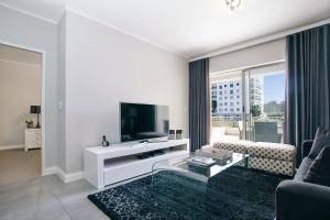 ein weißes Wohnzimmer mit einem TV und einem Sofa in der Unterkunft Superior Apartment Mayfair in Kapstadt