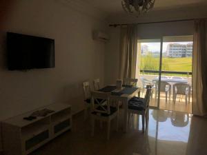 een eetkamer met een tafel en stoelen en een televisie bij SeaView Appart Chez Hicham in Asilah