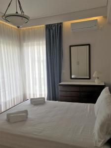 1 dormitorio con 1 cama blanca grande y espejo en Grace Apartments, en Loutraki