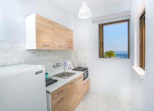 Elle comprend une petite cuisine avec un évier et une fenêtre. dans l'établissement Pefkides Aegina Boutique Apartments, à Agia Marina