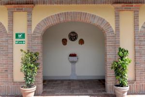 une arche avec deux plantes en pot devant un bâtiment dans l'établissement Borgo Ai Lecci, à Orentano