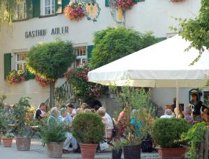 a group of people sitting at a restaurant in front of a building at Adler Oberdorf in Langenargen