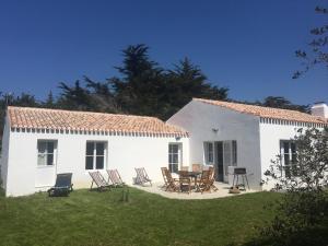Casa blanca con mesa y sillas en el patio en Les Genets, en Ker borny