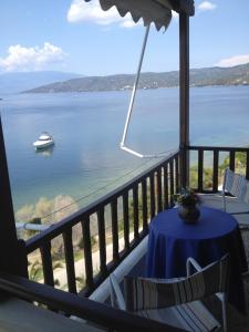 a balcony with a table and a boat in the water at Blue Bay in Milína